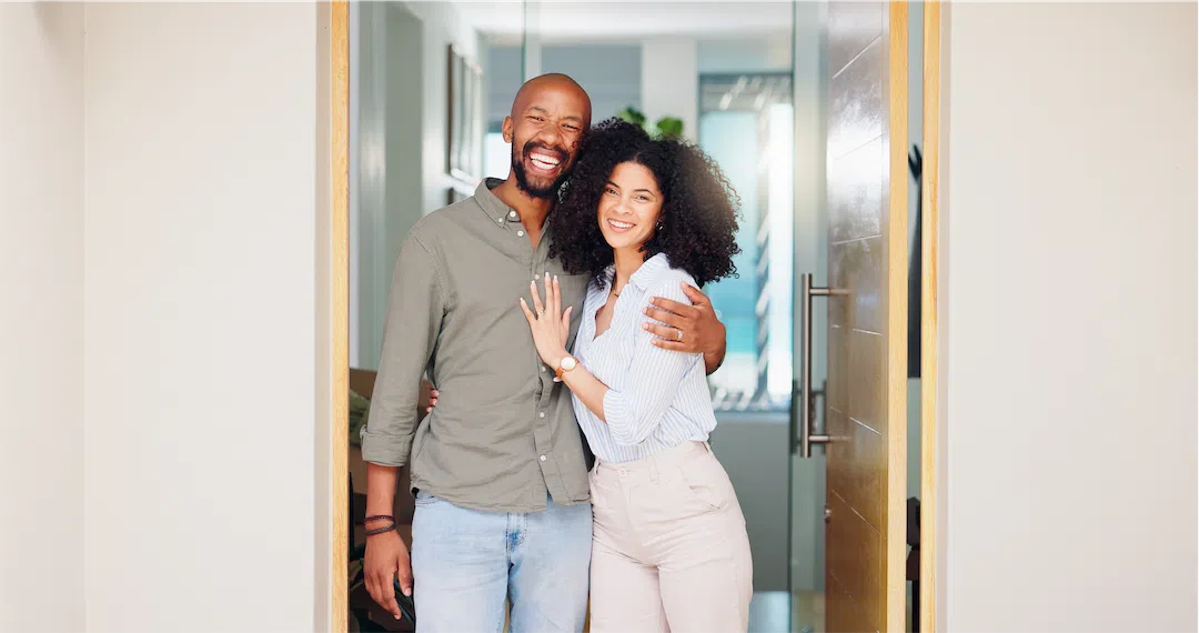 A happy couple hugs at the front door of their well-maintained rental home in Anchorage.